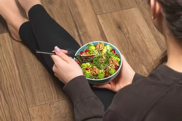 Girl sitting on the floor with a bowl of vegetable salad (Flip 2020)