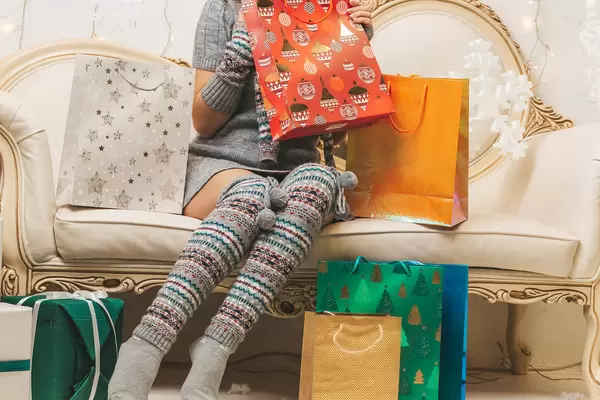 Girl sitting on the sofa with colorful bright gift bags