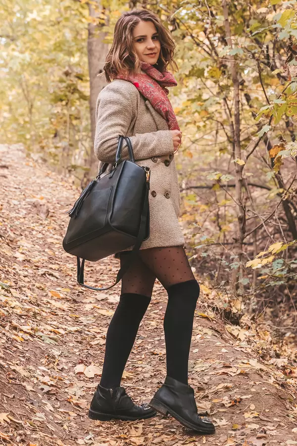 Girl walks with a handbag in the autumn forest