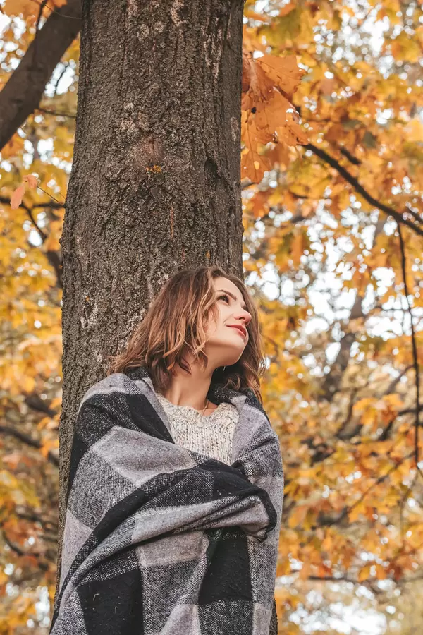 Girl with a plaid near a large autumn oak