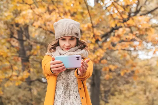 Girl with a smartphone in her hands in the autumn forest