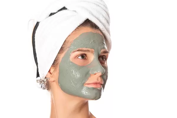Girl with facial clay mask, beauty treatments