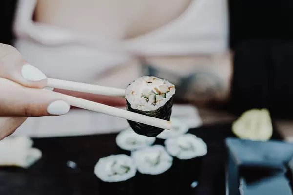 Girl's hand holding sushi with sushi sticks