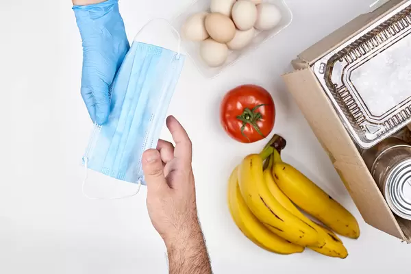 Giving a face mask with food packs to a needy person