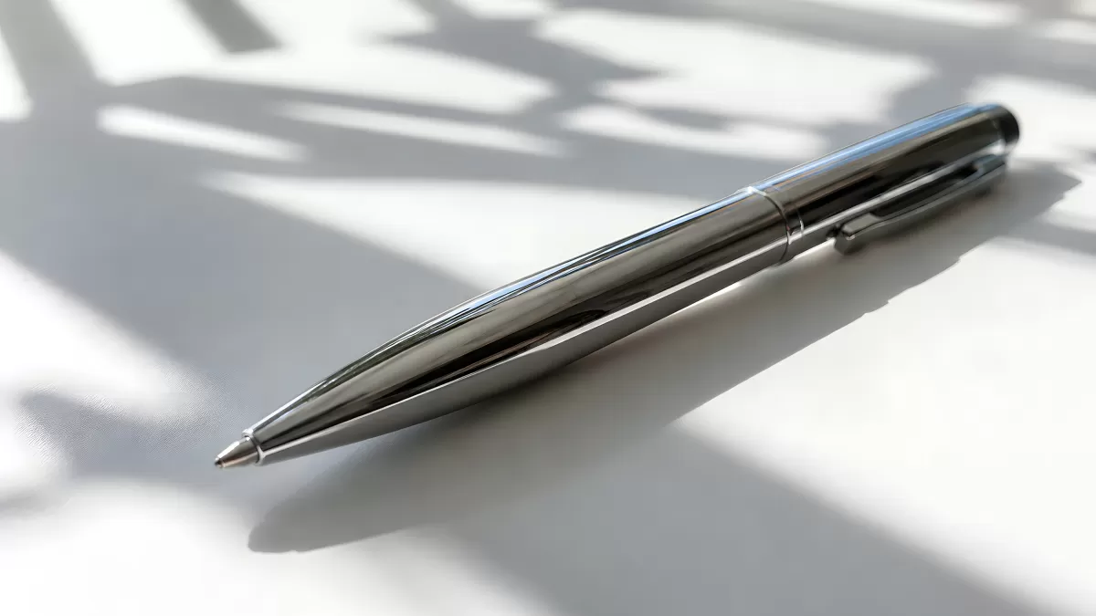 Glänzender Kugelschreiber aus Metall auf weißer Fläche