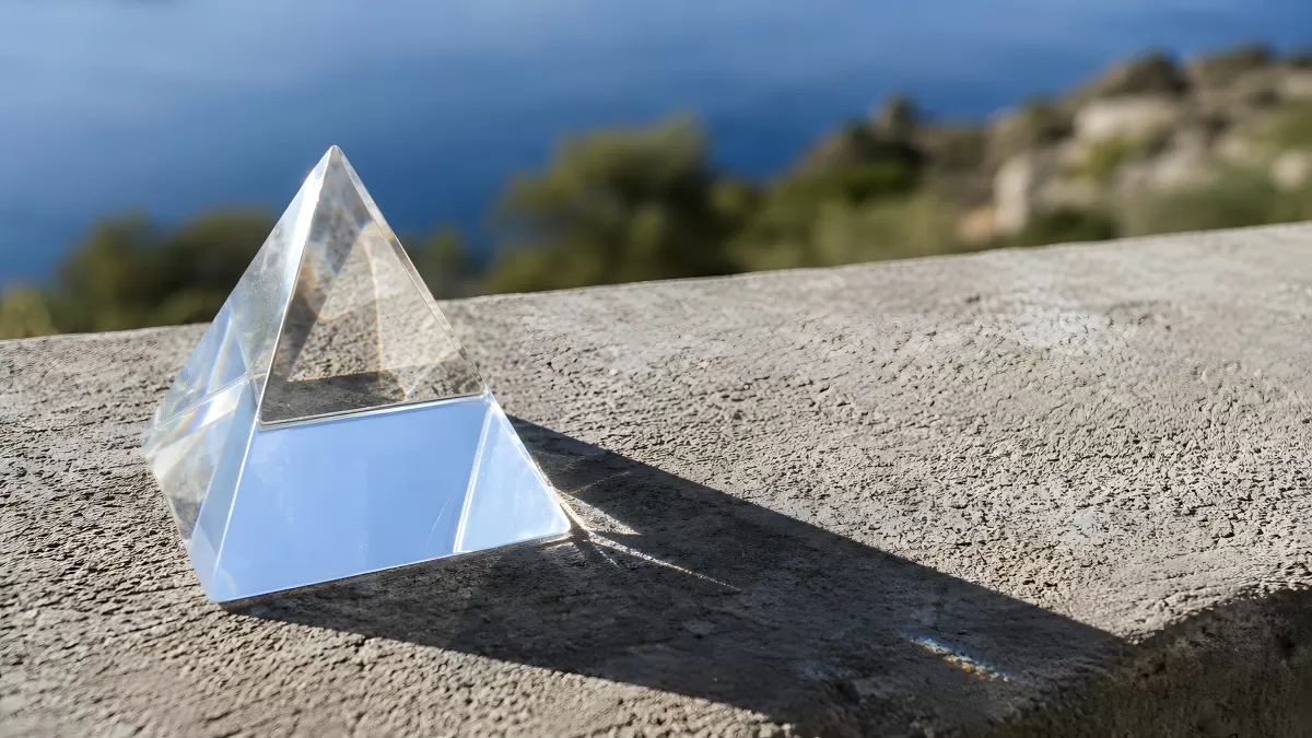 Gläserne Kristallpyramide auf Steinmauer am Meer