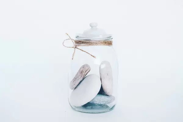 Glas mit Deckel voll mit Steinen vor weißem Hintergrund