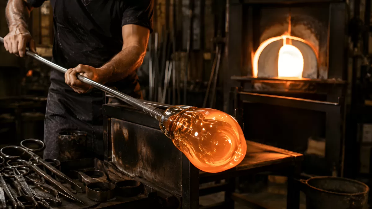 Glasbläser formt glühende Glasmasse in der Werkstatt