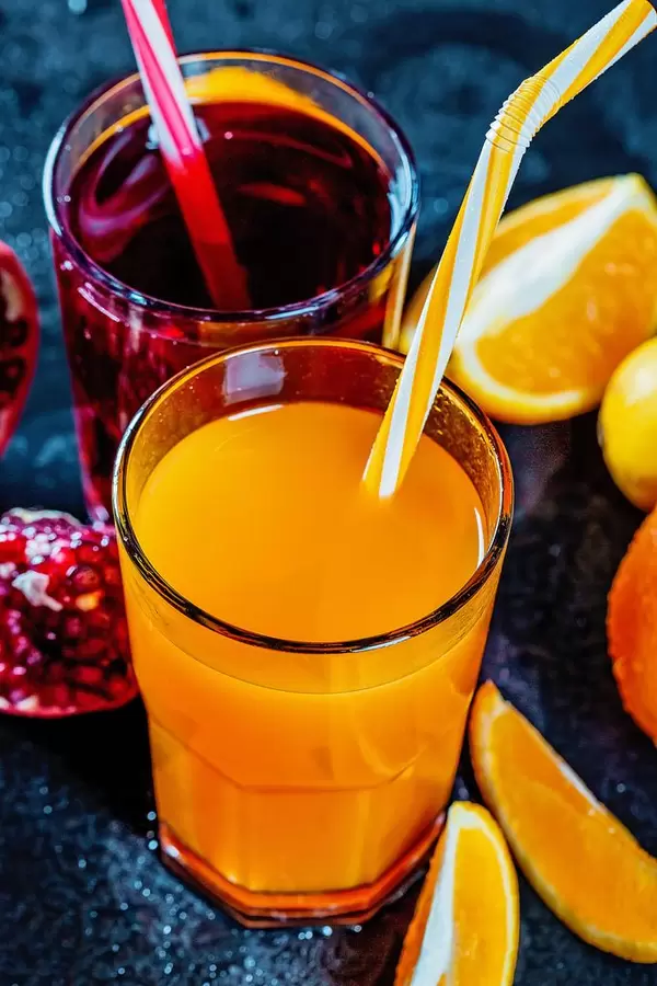 Gläser mit frischen Granatapfel und Orangensaft mit Zitronen, Orangen und Granatäpfeln auf dunklem Hintergrund