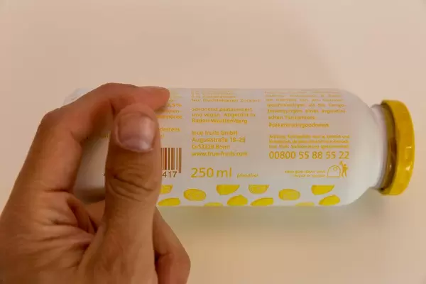 Glasflasche des Smoothie-Herstellers True Fruits, im Frühlingsdesign, mit schonend pasteurisiertem und veganem Inhalt