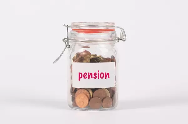 Glasgefäß als Sparschwein und der Aufschrift "Pension", besteht aus wenig Kleingeld