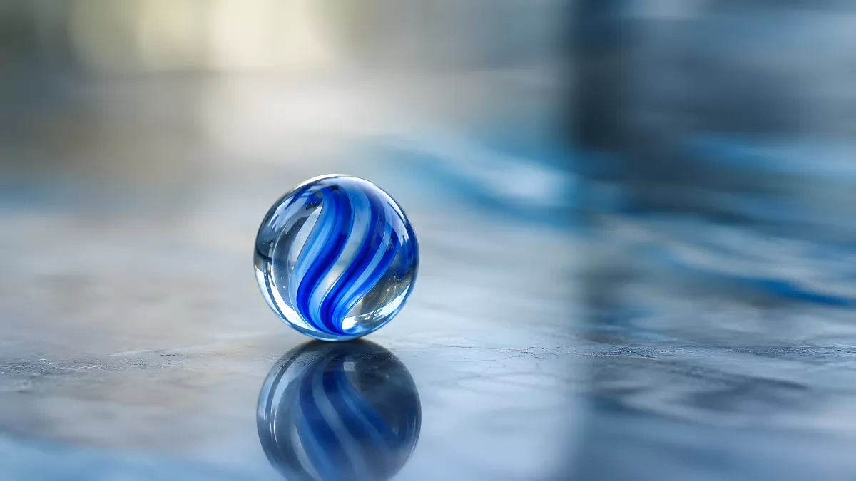 Glasmurmel mit blauen Spiralen auf spiegelnder Fläche