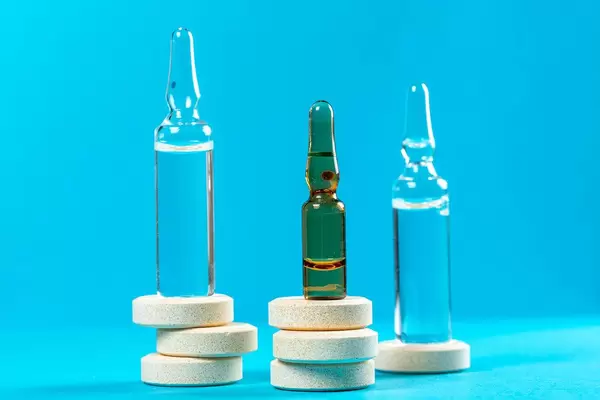 Glass ampoules with large round pills on blue background