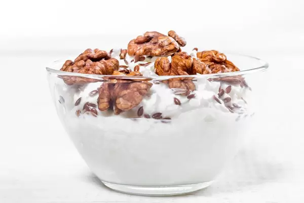Glass bowl with cottage cheese, nuts and flax seeds on white wooden background (Flip 2019)
