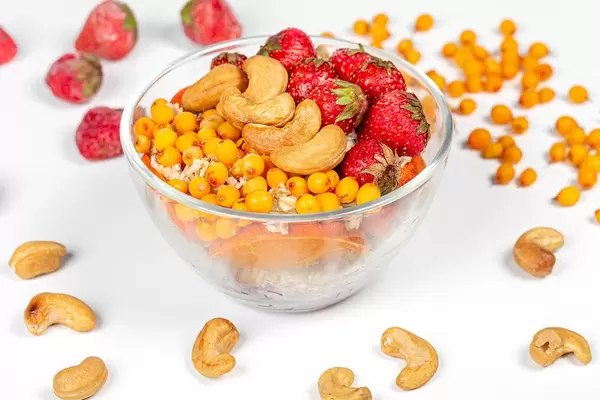 Glass bowl with oatmeal, strawberries, sea buckthorn berries and cashew nuts (Flip 2020)