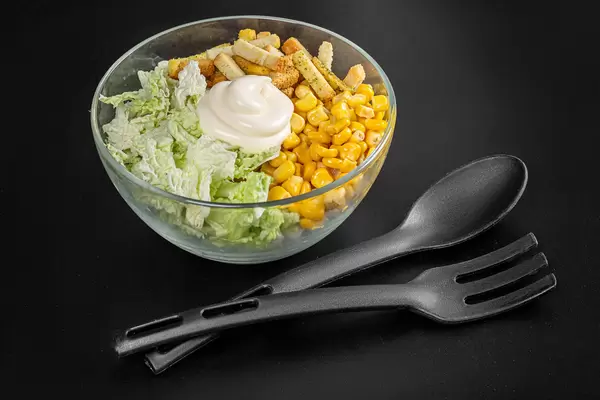 Glass bowl with peking cabbage salad with corn and rusks