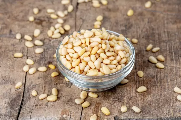 Glass bowl with pine nuts on an old wooden background (Flip 2020)