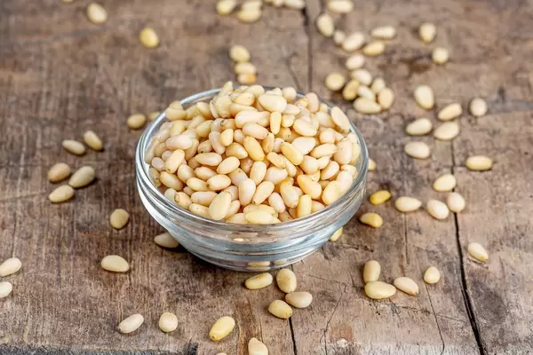 Glass bowl with pine nuts on an old wooden background