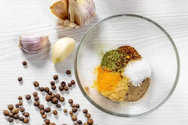Glass bowl with spices on white wooden background. Top view