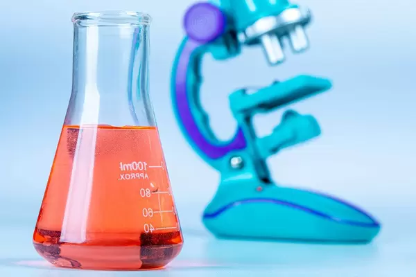 Glass flasks with red solution with a microscope in the background (Flip 2020)