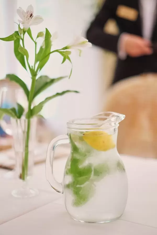 Glass jug of cold lemonade on a light background cafe. Pitcher lemon water with mint. Cold lemonade box  Flip 2019