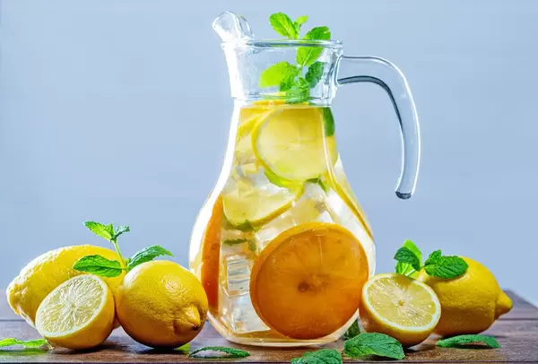 Glass of lemonade with ice cubes and mint leaves on wooden background