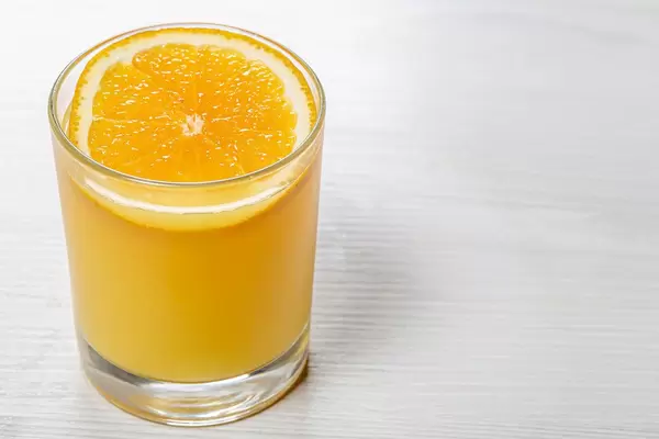 Glass of orange juice with a slice of orange on white wooden background (Flip 2019)