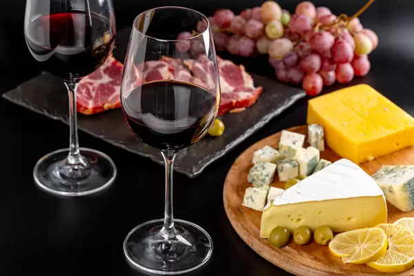 Glasses of red wine on a dark background with various delicious snacks