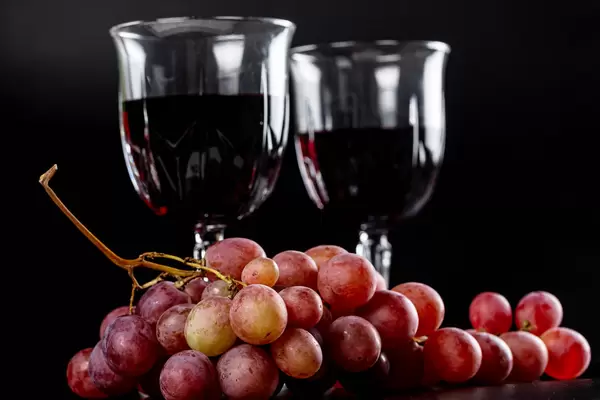 Glasses of red wine with fresh grapes on a dark background