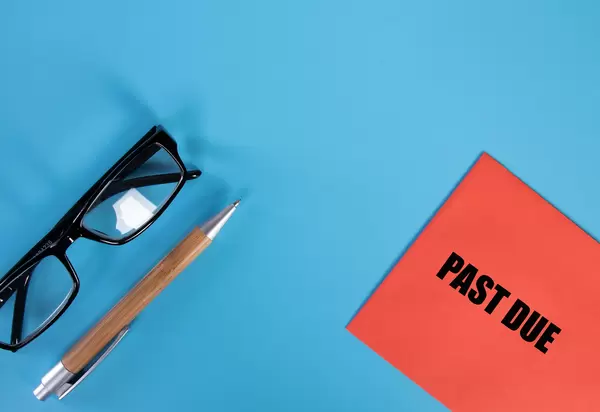 Glasses, pen and red envelope with Past Due text on blue background