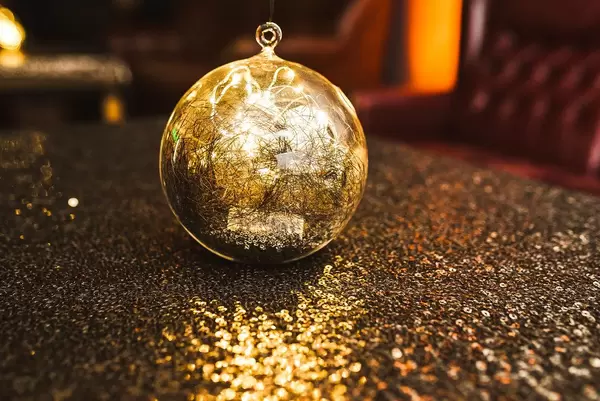 Glitzernde goldene Kugel zur Dekoration mit Lichtern auf einem Tisch