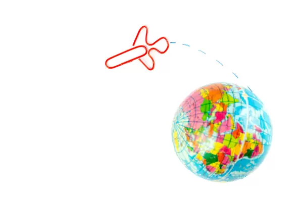 Globe model with airplane paper clip flying on the white background, transport and travel concept