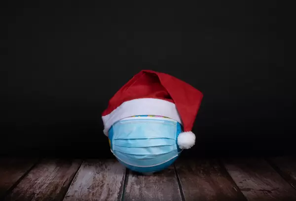 Globe with face mask and Christmas hat on black background
