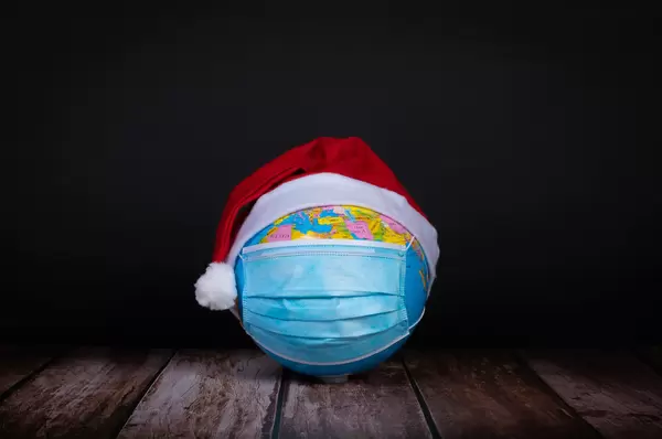 Globe with face mask and red Christmas hat on black background