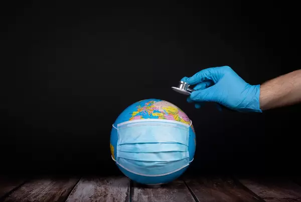 Globe with medical face mask and hand with stethoscope