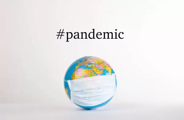 Globe with medical mask and #pandemic text on white background.jpg