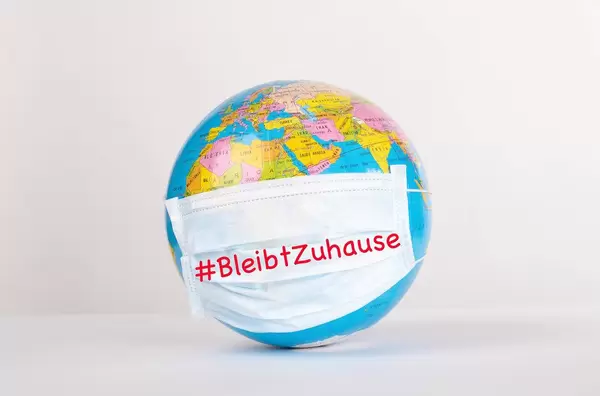 Globe with medical mask on white background and #BleibtZuhause text
