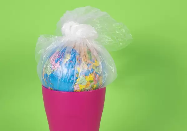 Globus in Plastiktüte im Mülleimer - Konzept zum Plastikproblem