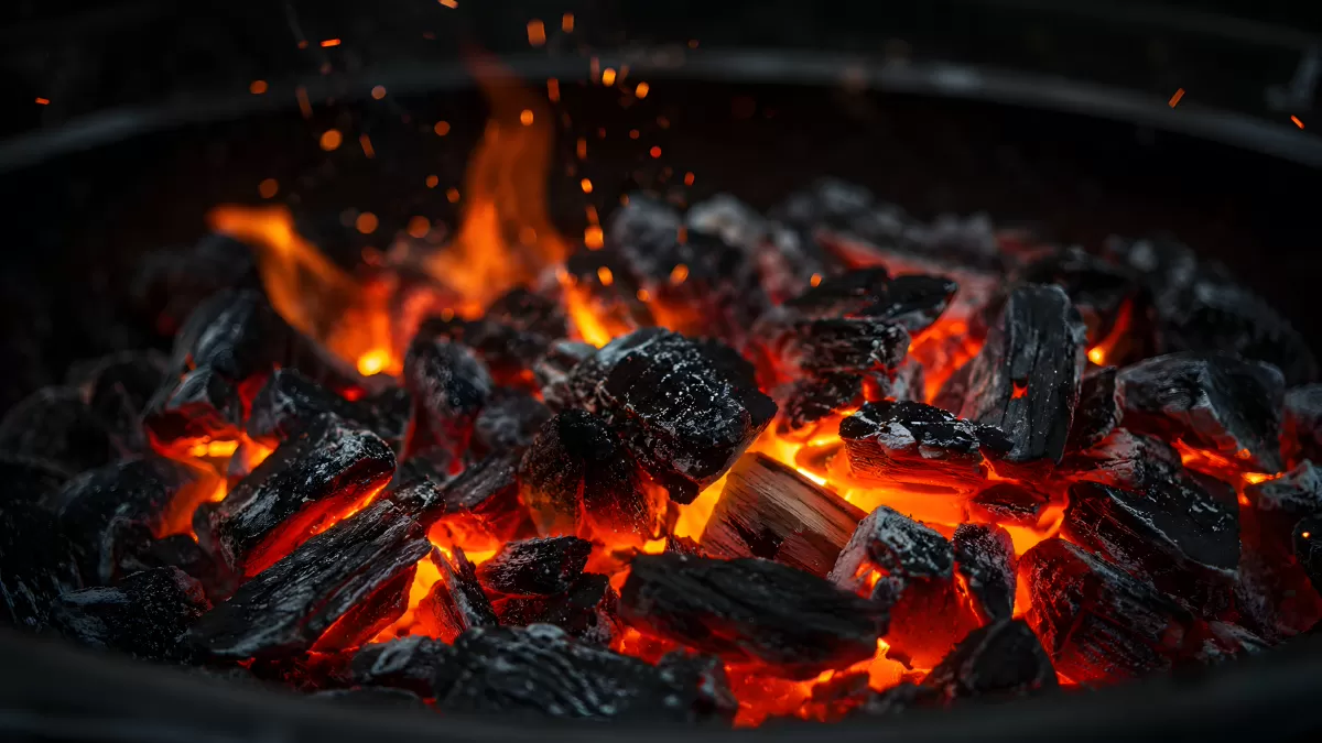 Glühende Holzkohle in einem runden Grill mit Flammen