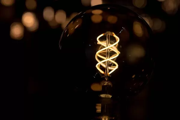 Glühbirne künstlerisch fotografiert im Dunkeln mit lediglich erhelltem Leuchtdraht
