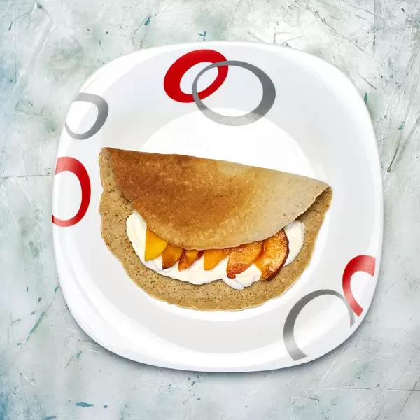 Gluten free oat-based pancakes with fresh yogurt and peach slices