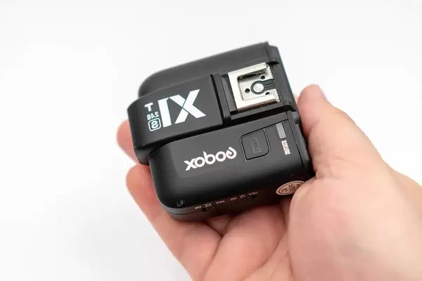 Godox X1 flash controller in the hand above white background (Flip 2020)