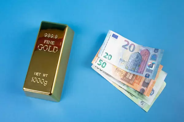 Gold brick with Euro banknotes on blue background