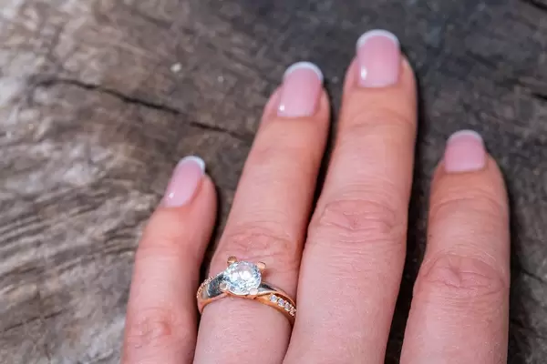 Gold ring on woman's finger on old wooden background (Flip 2019)