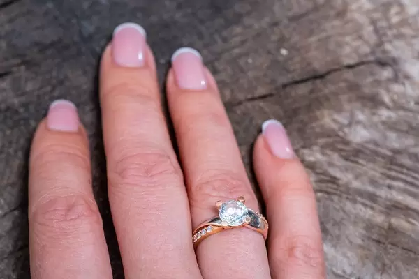 Gold ring on woman's finger on old wooden background