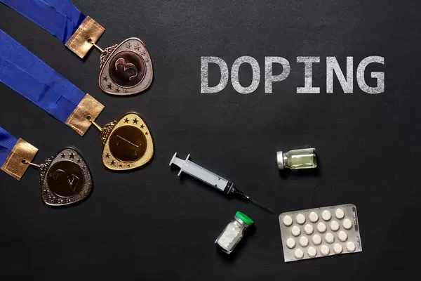 Gold, silver and bronze medal and doping syringe and pills on a dark background