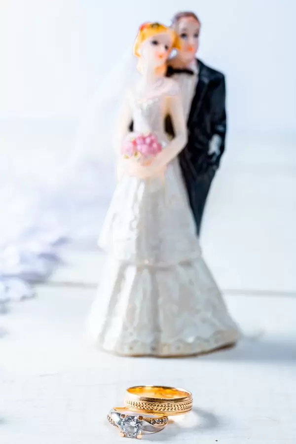 Gold wedding rings, behind the figure of the bride and groom