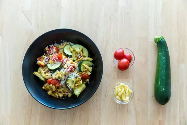 Goldbraun gebratene Spätzle mit getrockneten Tomaten und Zucchini inklusive Zutaten. Draufsicht