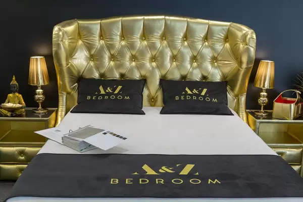 Golden bed next to golden lamps and tables and a Buddha figure in a luxurious hotel room