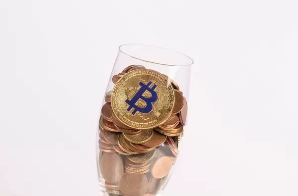 Golden Bitcoin and coins in champagne glass